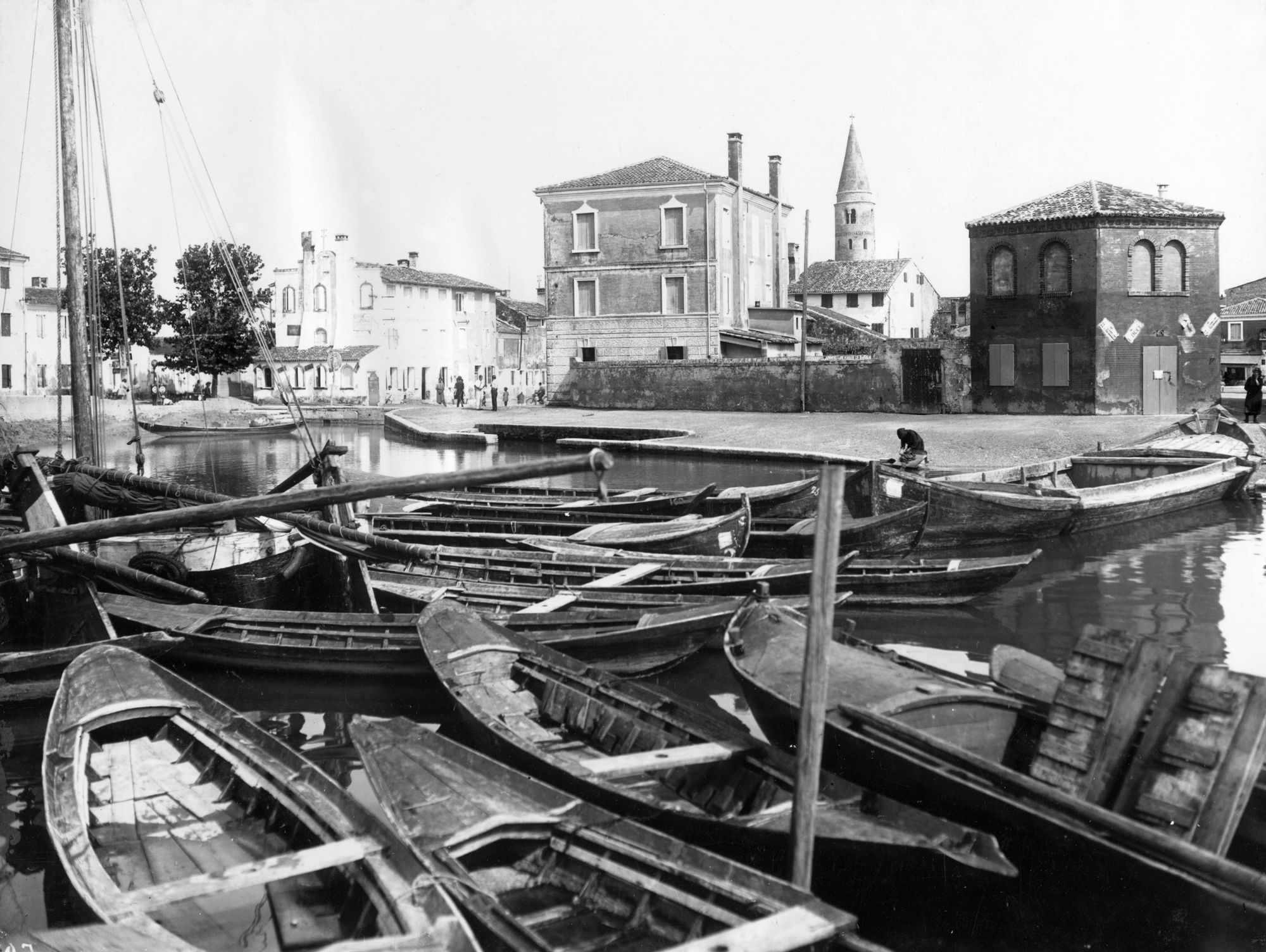 Foto d'archivio: barche da pesca ormeggiate nel canale di Caorle con il campanile cilindrico sullo sfondo